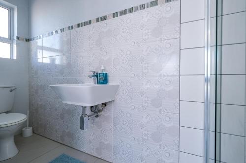 a white bathroom with a sink and a toilet at De Bakke Terrace 26 in Mossel Bay