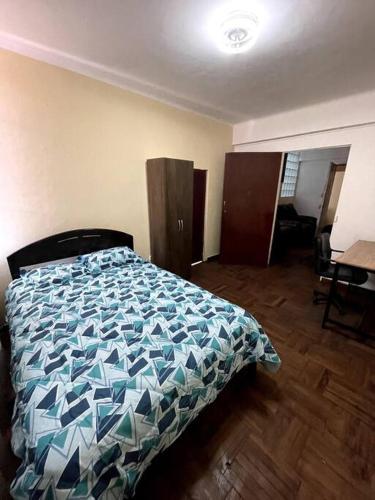 Schlafzimmer mit einem Bett mit blauer Decke in der Unterkunft Departamento con vista a la Plaza in Cajamarca