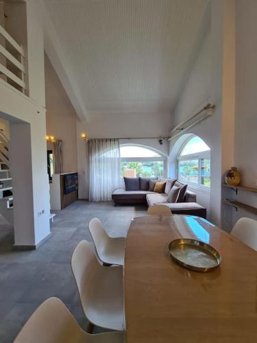 a large living room with a table and chairs at Cento Blu Villa in Gouvia
