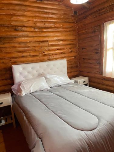 Cama en habitación con pared de madera en Rincón del Sur en San Miguel del Monte