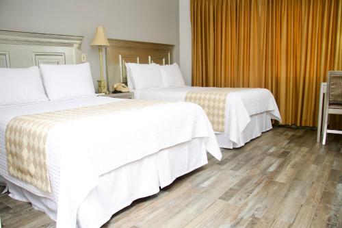duas camas com lençóis brancos num quarto de hotel em Hotel La Quinta em La Ceiba
