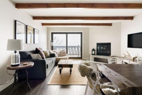 een woonkamer met een bank en een tafel bij Luxury Condominium with Rustic Minimalist Style in Mont-Tremblant
