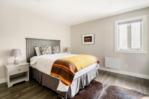 een witte slaapkamer met een groot bed en een raam bij Luxury Condominium with Rustic Minimalist Style in Mont-Tremblant