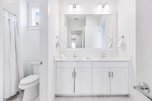 a white bathroom with a sink and a toilet at Palmilla Beach Resort: Luxury Gulf Getaway in Port Aransas