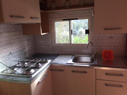 a kitchen with a stove and a sink and a window at Camping Edy in Diano Marina