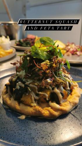 a pizza with greens on top of it on a table at The Bell Inn, Rickinghall in Rickinghall