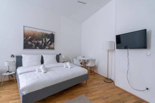 a bedroom with a bed and a flat screen tv at Cosy Apartment Naschmarkt I new furnished in Vienna