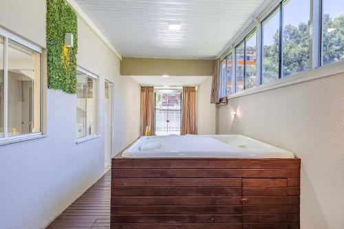 ein Badezimmer mit einer großen Badewanne und Fenstern in der Unterkunft Casa com Jacuzzi ideal para Férias de Famílias - 3 dorms 6 pessoas in Bombinhas