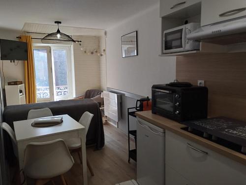 Il comprend une petite cuisine et un salon avec une petite table. dans l'établissement appartement cosy hyper centre de Cauterets, à Cauterets