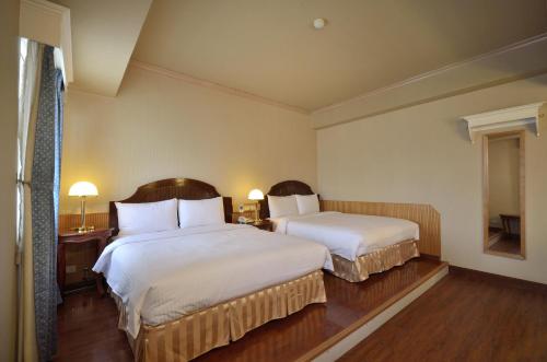 a hotel room with two beds and a window at Goodness Hotel in Kaohsiung