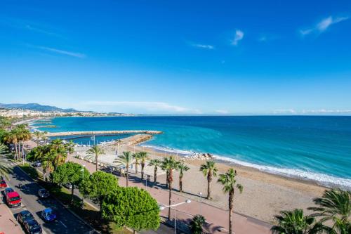 une vue aérienne d'une plage avec des palmiers et l'océan dans l'établissement Le Balcon sur la Baie - Welkeys, à Cagnes-sur-Mer