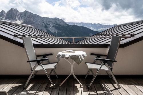 a balcony with a table and chairs and mountains at Berghotel Schlemmer in Bressanone