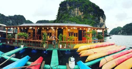 a person standing in front of a house in the water at Eco Floating Farm Stay Cai Beo in Cat Ba