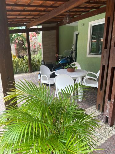 a patio with a table and chairs and a motorcycle at Cantinho do aconchego de Arembepe in Camaçari