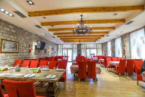 un restaurante con sillas y mesas rojas y una pared de piedra en Vila Falo, en Voskopojë