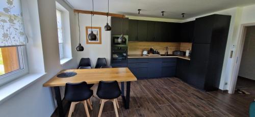 una cocina con una mesa de madera y algunos armarios negros en Apartmán U Ludvíčka, en Smržovka