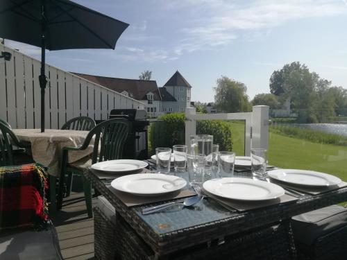a table with plates and glasses and an umbrella at Lovely Lakeside lodge for families and friends in South Cerney