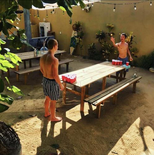 two men standing in front of a picnic table at La Palmera Hostel in Puerto Escondido