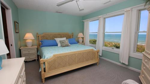sypialnia z łóżkiem z niebieskimi ścianami i oknami w obiekcie OCEANFRONT, Private Pool, Ocean Views, Beach Walkway, Hot Tub, WL1035, PiraSea w mieście Corolla