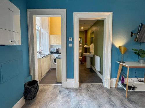 格拉斯哥的住宿－Cozy Studio Apartment of Glasgows West End，厨房设有蓝色的墙壁和走廊