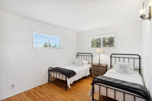 Duas camas num quarto branco com duas janelas em Toltec Hideaway em Albuquerque