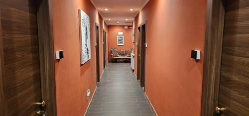 a hallway with orange walls and a long hallway with a chair at HOTEL BIJOUX in Pozzolo Formigaro