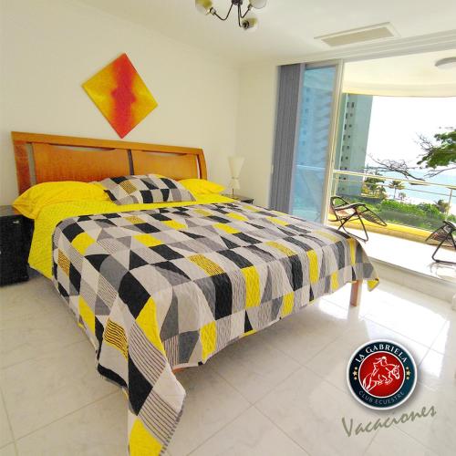 a bedroom with a bed with a yellow and black comforter at Departamento con 3 habitaciones, con capacidad para 8 personas, frente al mar in Tonsupa