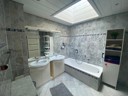 La salle de bains est pourvue de 2 lavabos, d'une baignoire et d'une baignoire. dans l'établissement Haus Holly, à Ruhpolding