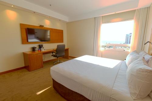 a hotel room with a bed and a desk and a window at Crowne Plaza Asunción by IHG in Asuncion