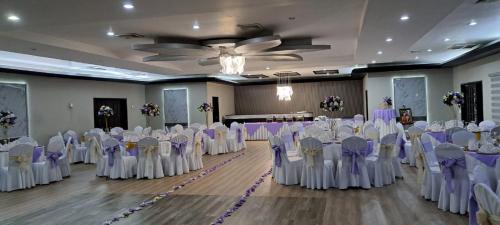 a banquet hall with white chairs and tables with purple bows at Hotel La Quinta in La Ceiba