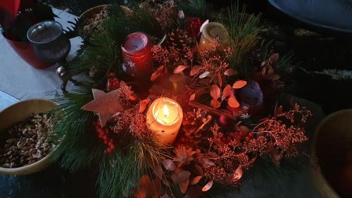 a candle in a vase with a christmas centerpiece at Apartments Beskydy in Prostřední Bečva