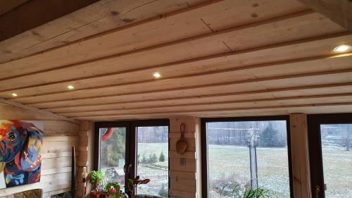 a room with a wooden ceiling and two windows at Apartments Beskydy in Prostřední Bečva