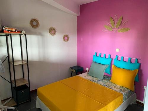 1 dormitorio con cama amarilla y almohadas coloridas en Maison de 2 chambres avec piscine privee spa et jardin clos a Riviere Salee, en Rivière-Salée
