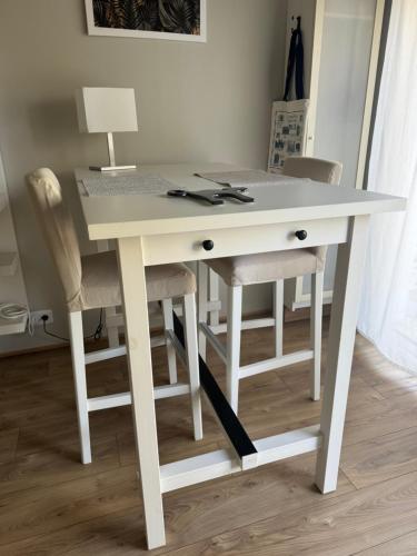 a white desk with two chairs and a lamp at Au Jardin de la Saudrune in Villeneuve-Tolosane