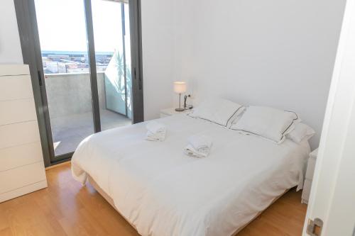 a white bed in a room with a large window at Casa Luz de Rajamanta - Terraza vistas a 1º línea y Parking in Barbate