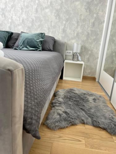 a bedroom with a bed with a furry rug on the floor at Apartman EMA in Banja Luka