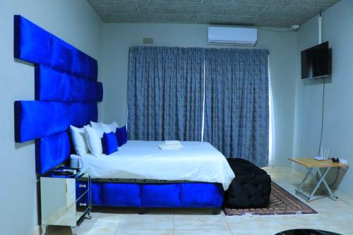 - une chambre bleue avec un lit et une fenêtre dans l'établissement La Maison Guesthouse, à Thohoyandou
