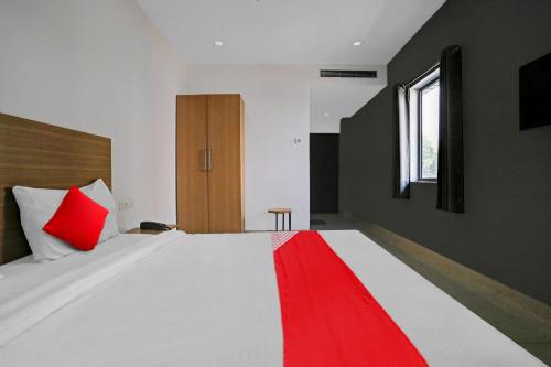 a bedroom with a large white bed with red accents at OYO Flagship 81093 Aroma guest House in Varanasi