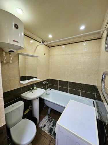 een badkamer met een toilet, een bad en een wastafel bij Аpartment on Аbdiova in Karagandy