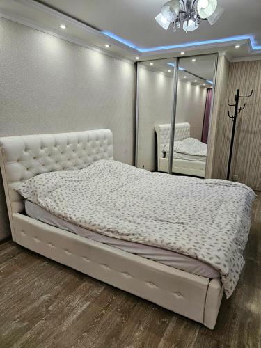 een slaapkamer met een wit bed en een spiegel bij Аpartment on Аbdiova in Karagandy