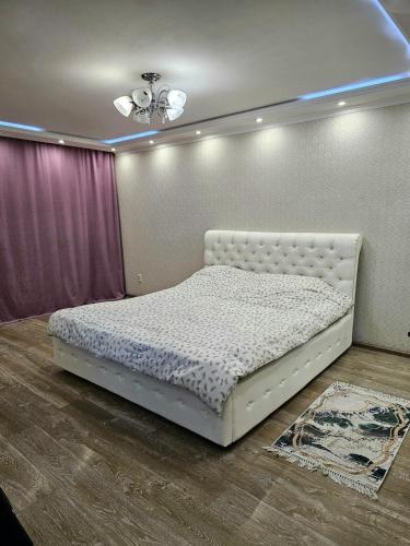 een slaapkamer met een wit bed in een kamer bij Аpartment on Аbdiova in Karagandy