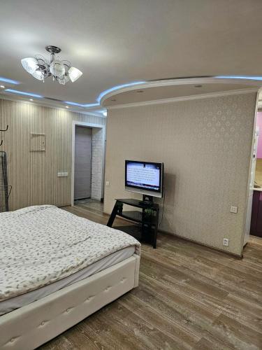 een slaapkamer met een bed en een flatscreen-tv bij Аpartment on Аbdiova in Karagandy