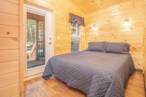 a bedroom with a bed in a wooden room at The Bear Den Cabin #12 at Blue Spruce RV Park & Cabins in Tuckerville