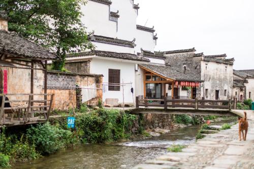 a bridge over a river in an asian village at Banyan Tree Huangshan in Huangshan