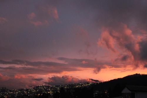 a cloudy sky with a city in the distance at sunset at Casa de Tulia in Quito