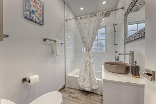 a white bathroom with a sink and a toilet at Mango Manor - Walk to Las Olas! in Fort Lauderdale