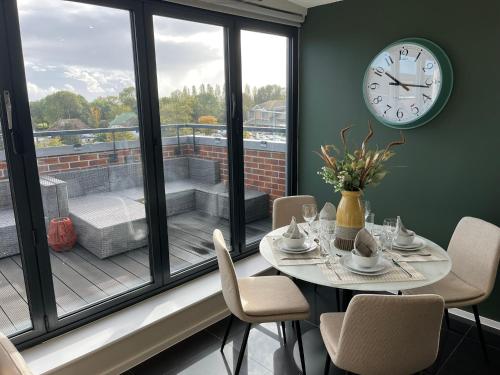 une salle à manger avec une table et une horloge sur une fenêtre dans l'établissement Stunning Luxury 3 Bed Penthouse Sleeps 2 to 6, à Hythe
