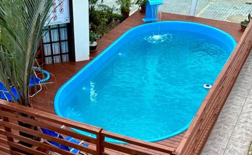 a large blue pool on a deck with a bench at Pousada Aconchego do Beija Flor in Bombinhas