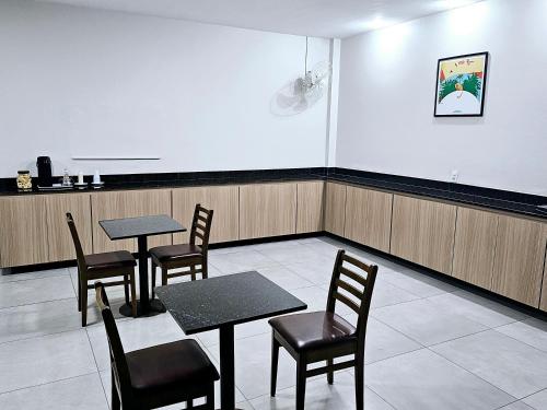 a waiting room with tables and chairs and a white wall at HOTEL INDIANO in Rio Bonito