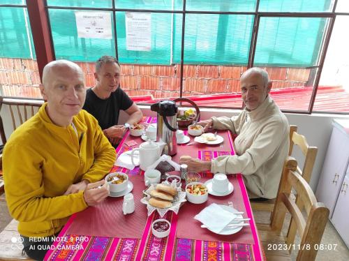 un grupo de tres hombres sentados en una mesa comiendo comida. en Welcome Cusco Hostel, en Cusco